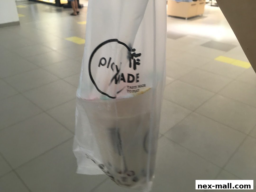 A person holds a plastic bag with the PlayMade logo containing a drink.