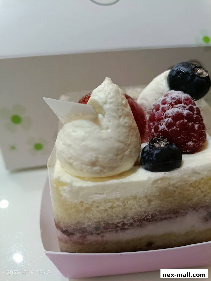 A slice of cake topped with whipped cream, raspberries, blueberries, and strawberries.