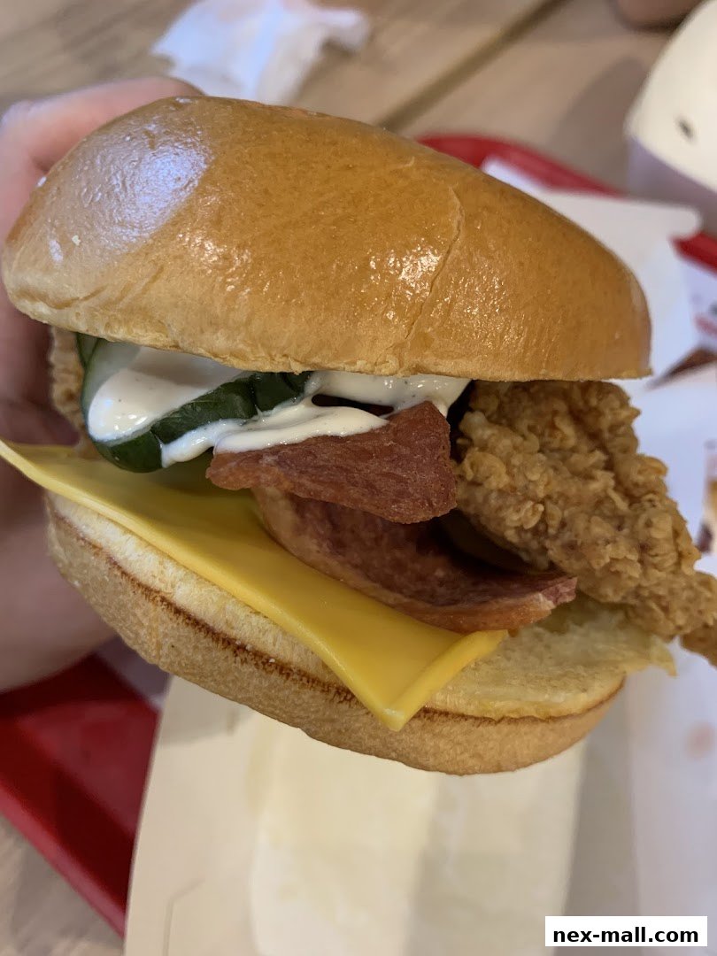 A close-up shot of a delicious KFC chicken sandwich with cheese and pickles.