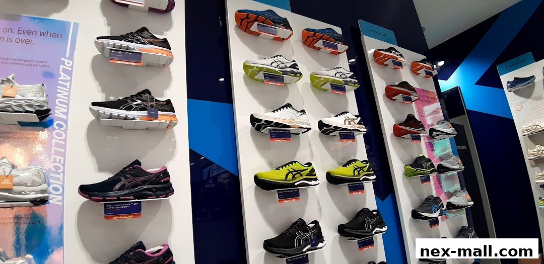 A display of various ASICS running shoes on shelves, showcasing different models and colors.