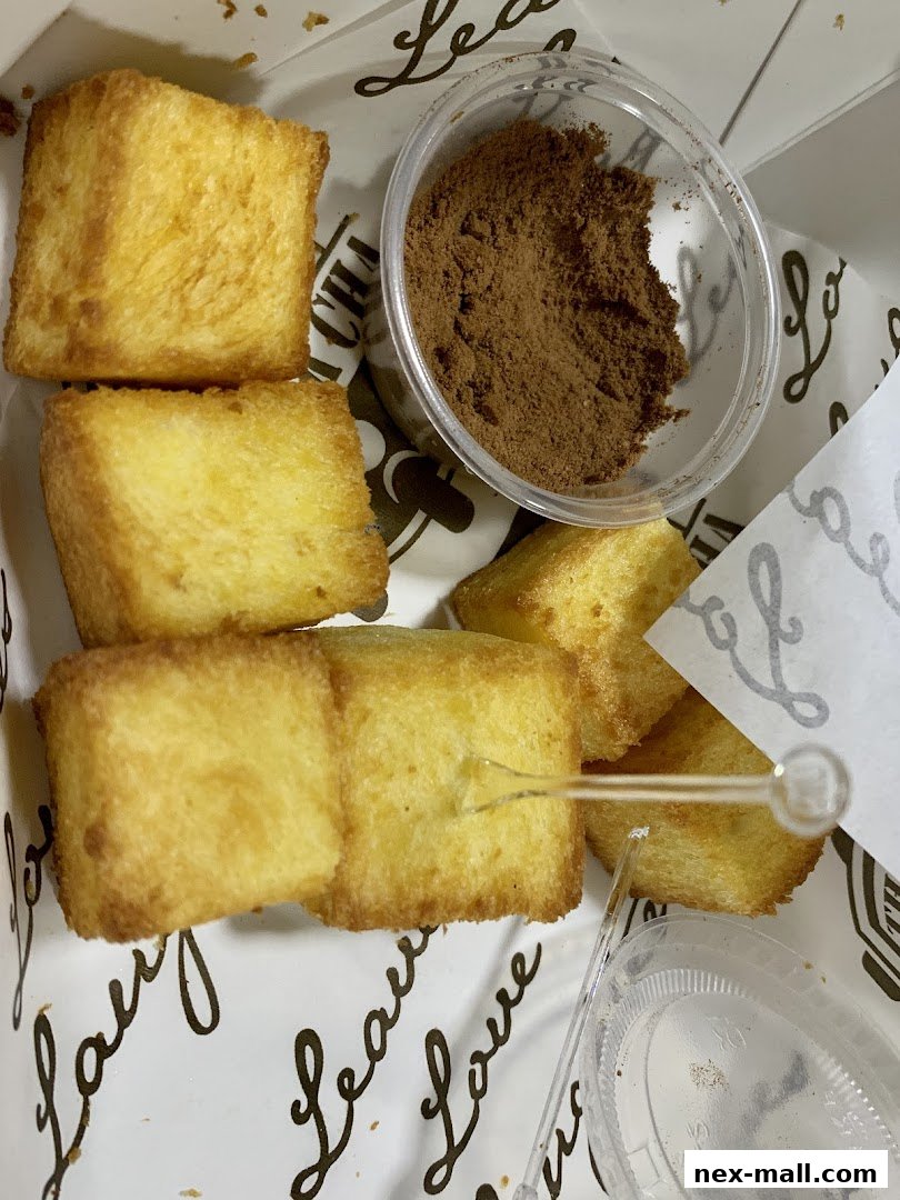 Golden brown toast cubes served with a side of cinnamon powder in a clear container.