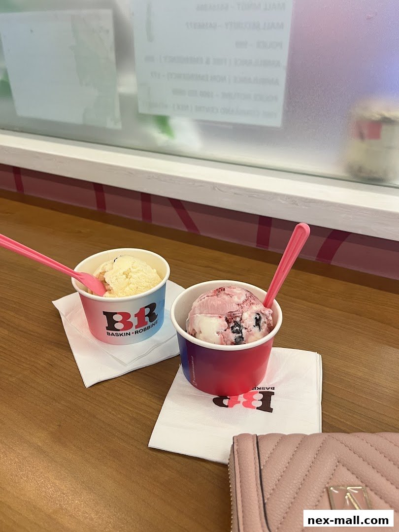 Two cups of Baskin-Robbins ice cream with spoons on a wooden table.