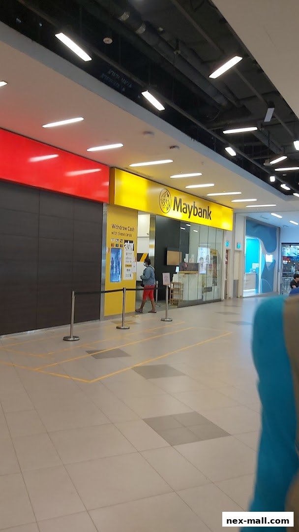 A Maybank branch entrance with a yellow facade and a person standing near an ATM.