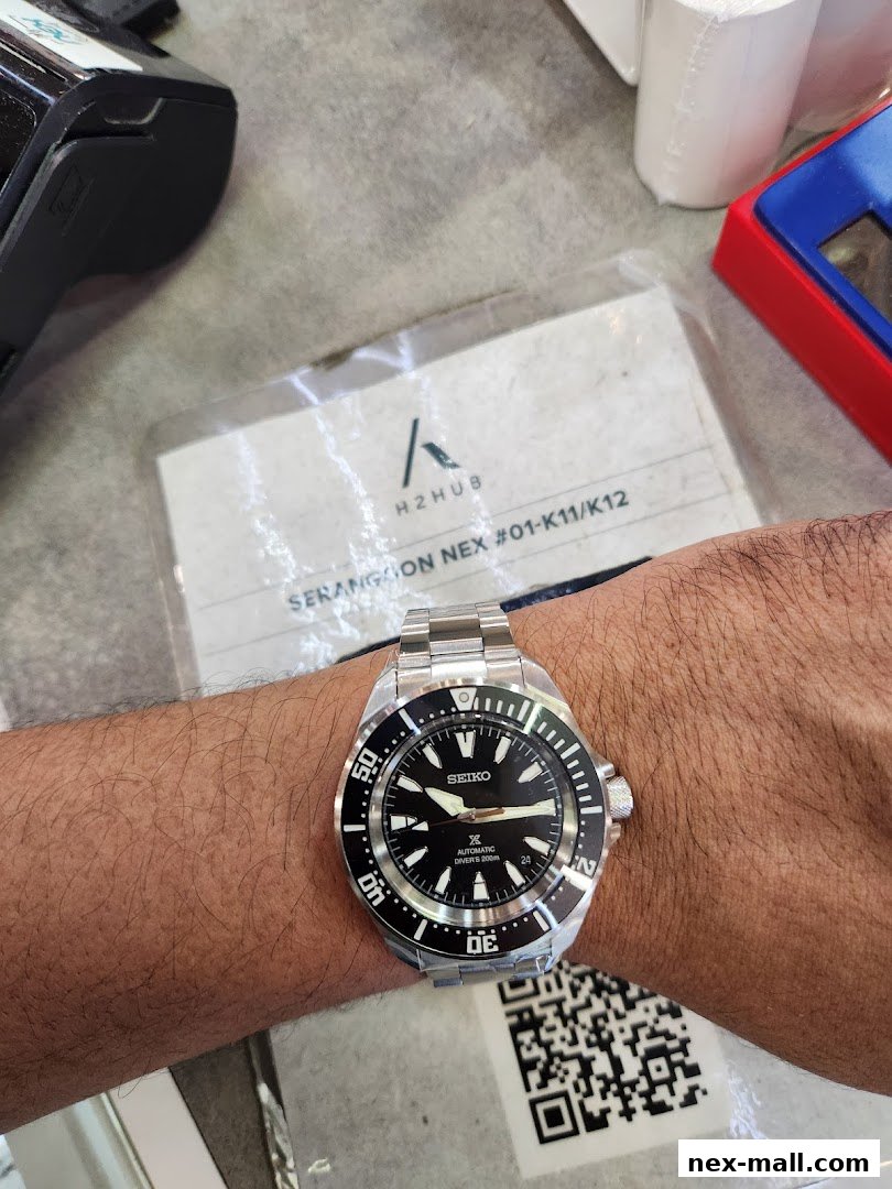 A person wearing a Seiko automatic diver's watch with a black dial.
