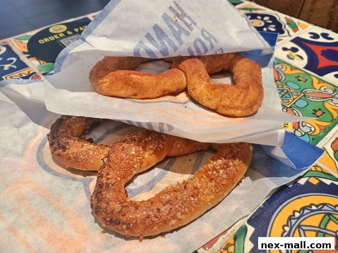 Two types of Auntie Anne's pretzels, one with cinnamon sugar and another with nuts, served in a paper bag.