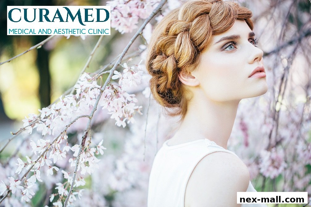A woman with braided hair poses with delicate pink blossoms.
