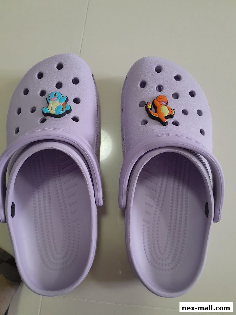 A pair of light purple Crocs adorned with Pokémon charms, specifically Squirtle and Charmander.