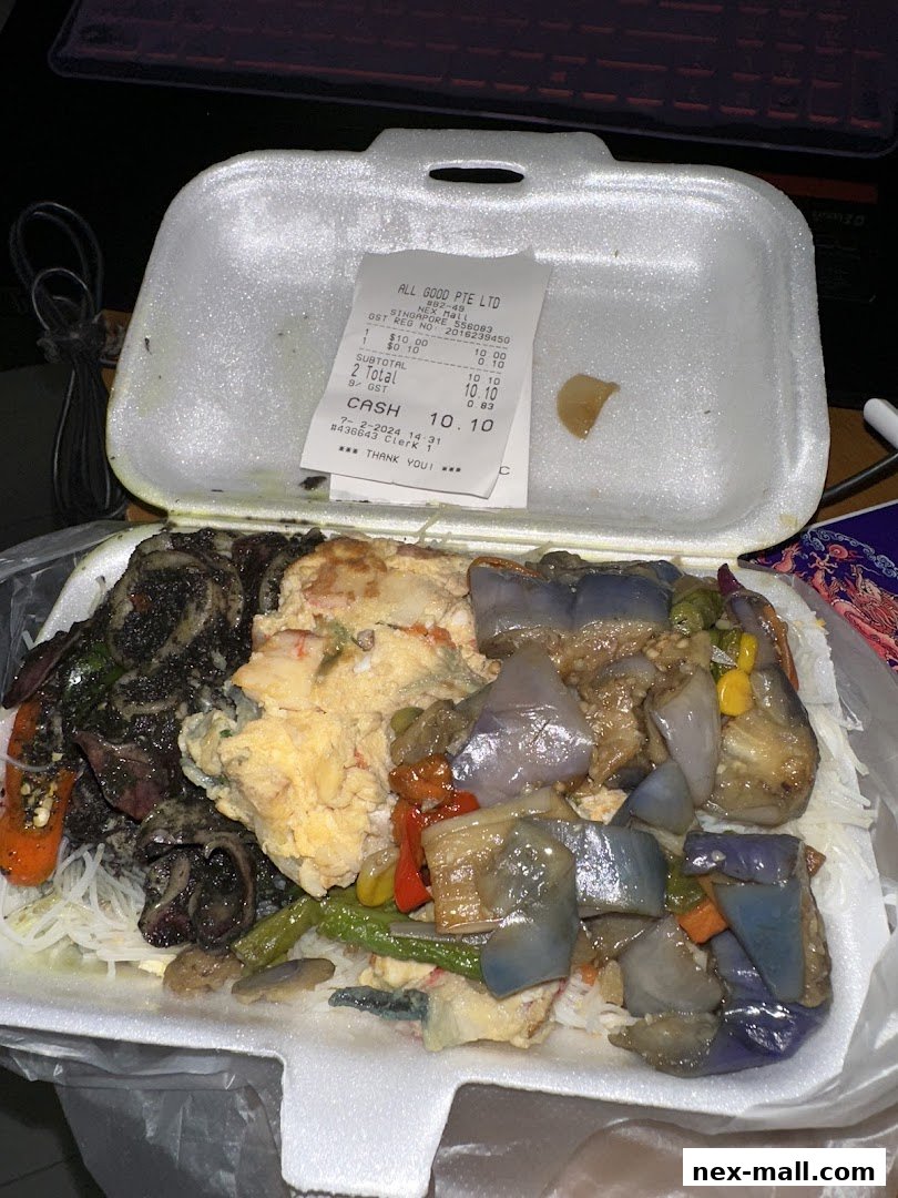 A takeout container filled with a meal, including noodles, scrambled eggs, and various vegetables.