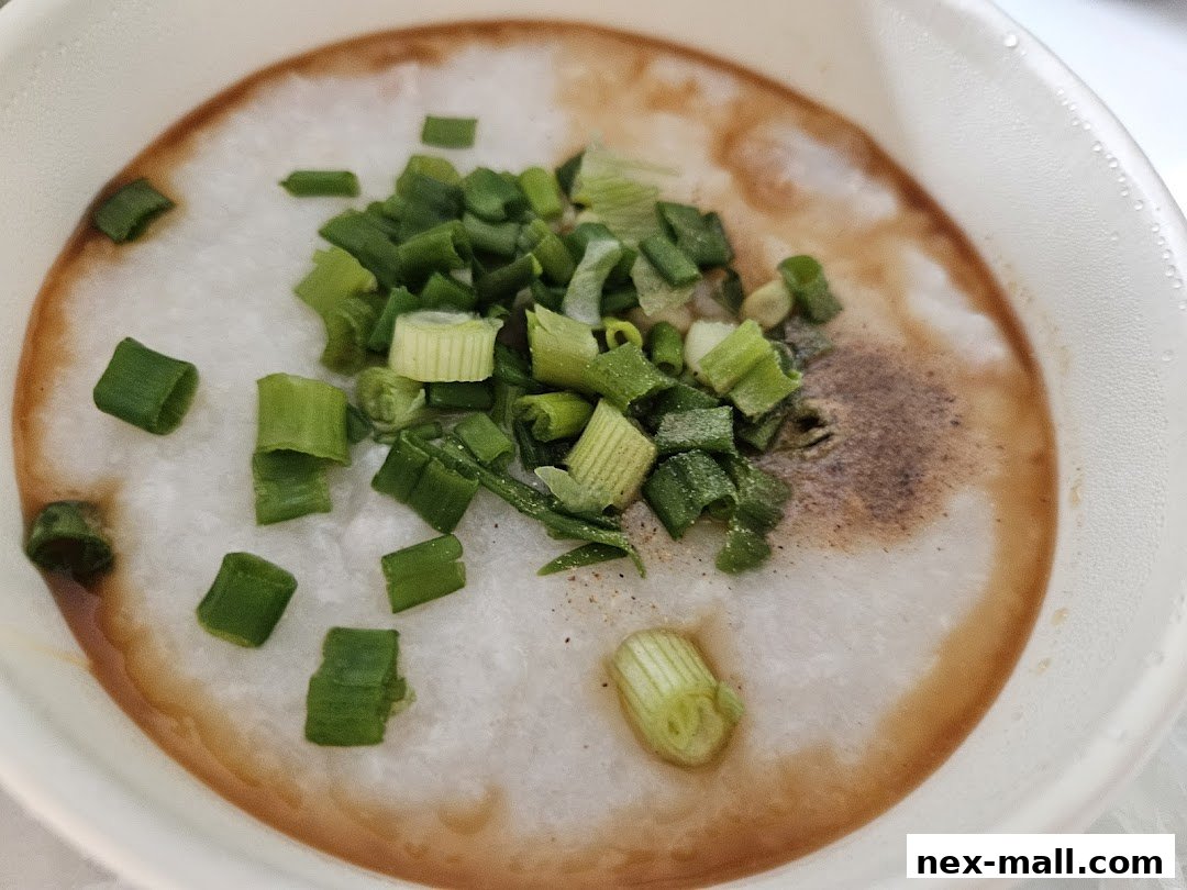A close-up of a bowl of congee topped with chopped scallions and pepper.