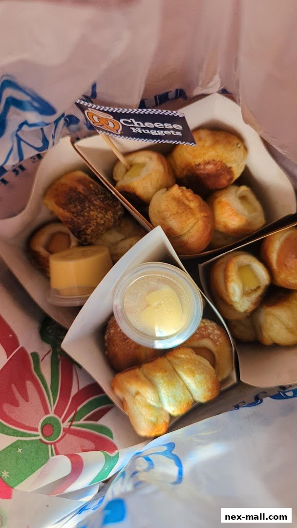 A bag filled with Auntie Anne's Cheese Nuggets and dipping sauce.
