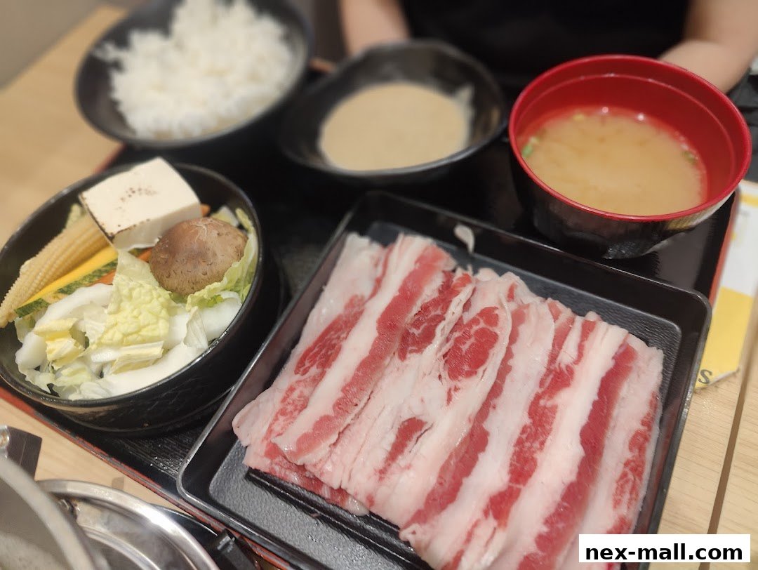 A close-up of a Japanese meal featuring thinly sliced beef, vegetables, rice, and miso soup.