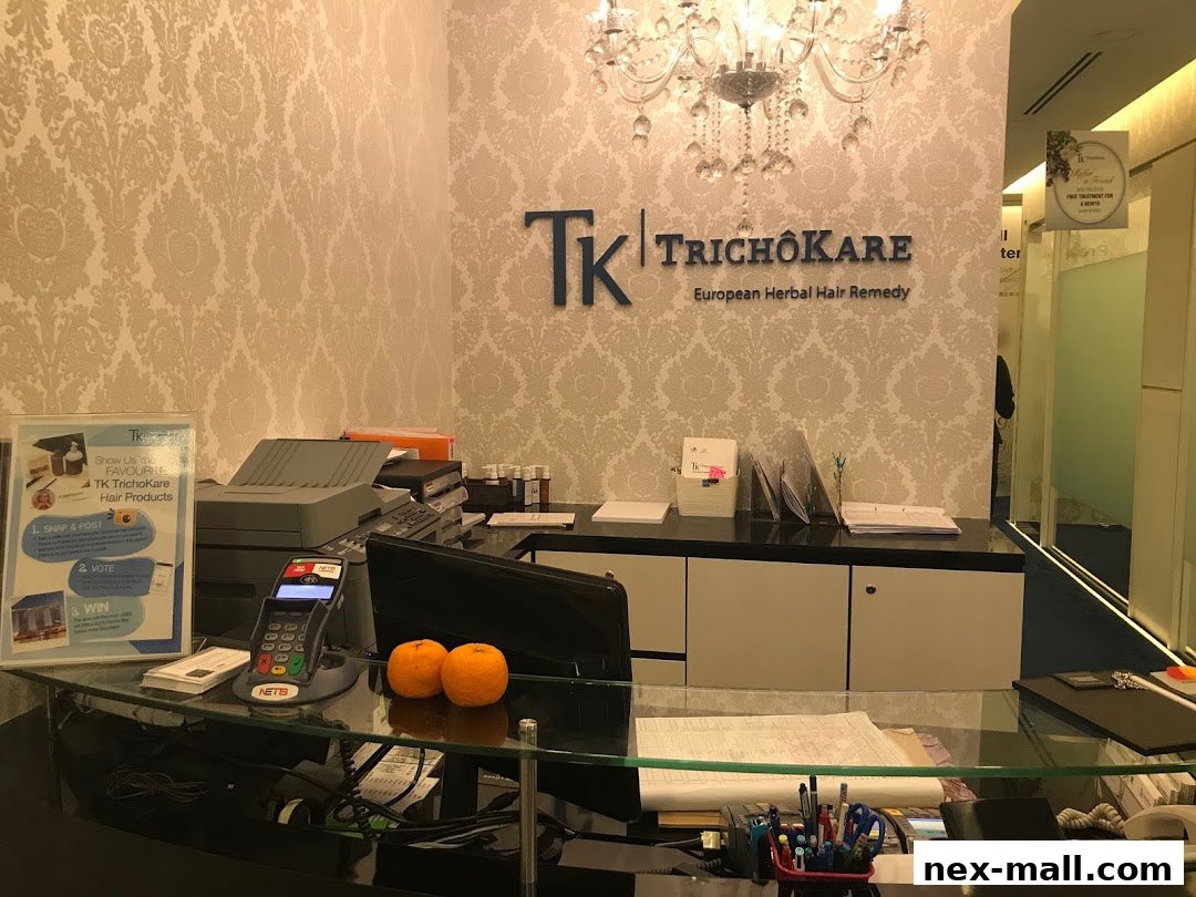 The reception area of TK TrichoKare, featuring the brand logo, a chandelier, and a counter with a printer and payment terminal.