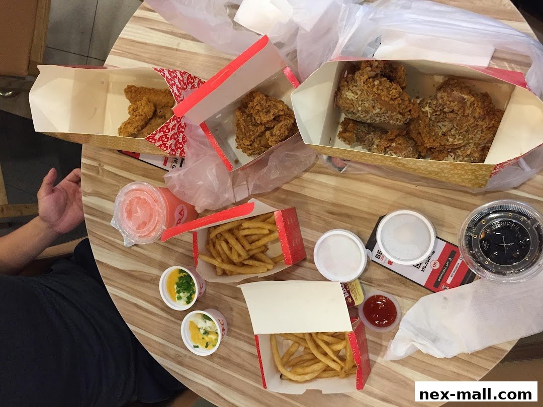A table laden with KFC fried chicken, french fries, drinks, and dipping sauces.