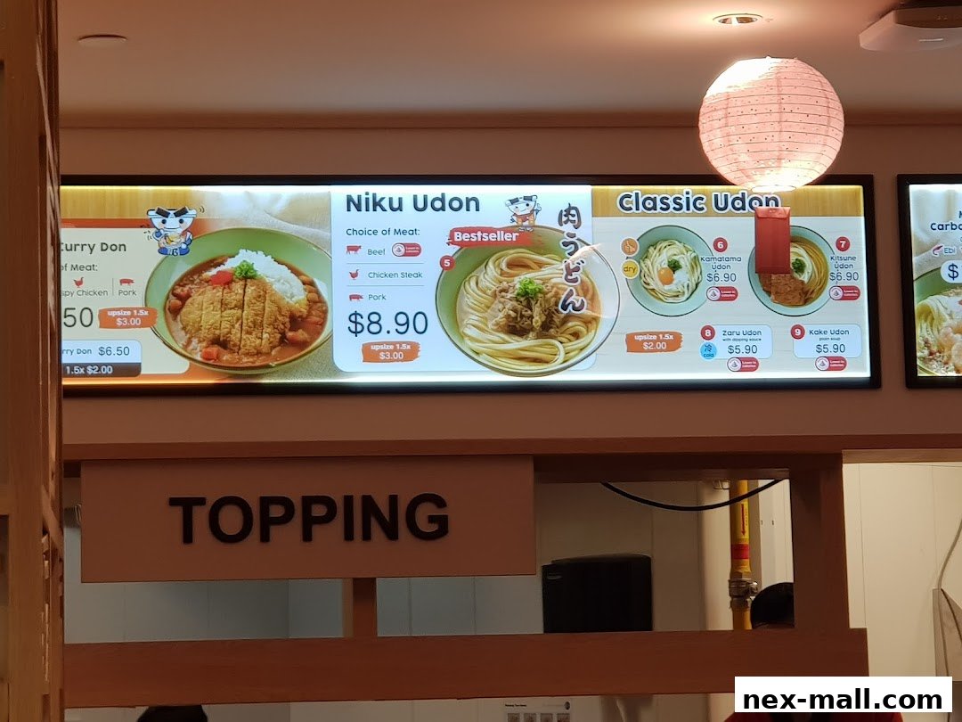 A brightly lit menu board displaying various udon and donburi dishes with prices.