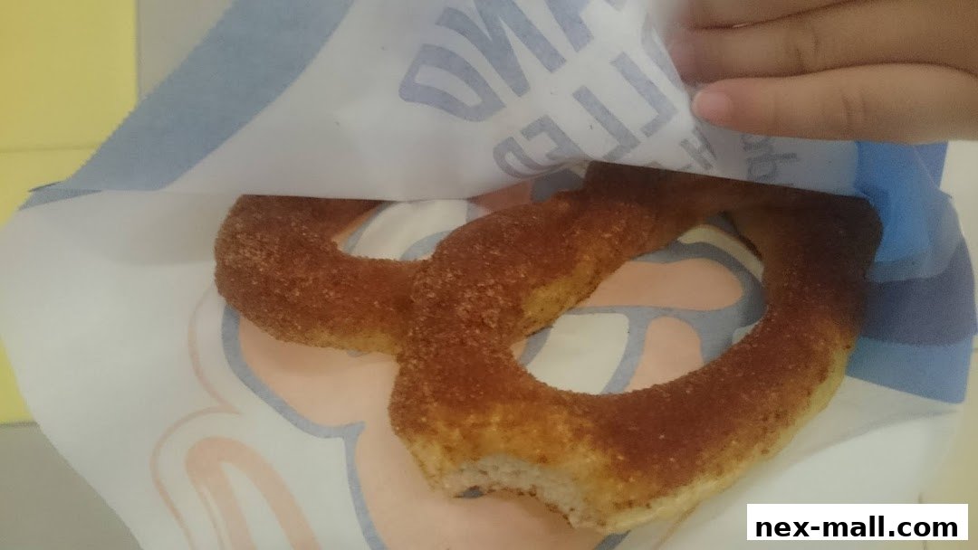 A cinnamon sugar pretzel is shown in a paper bag with the Auntie Anne's logo.
