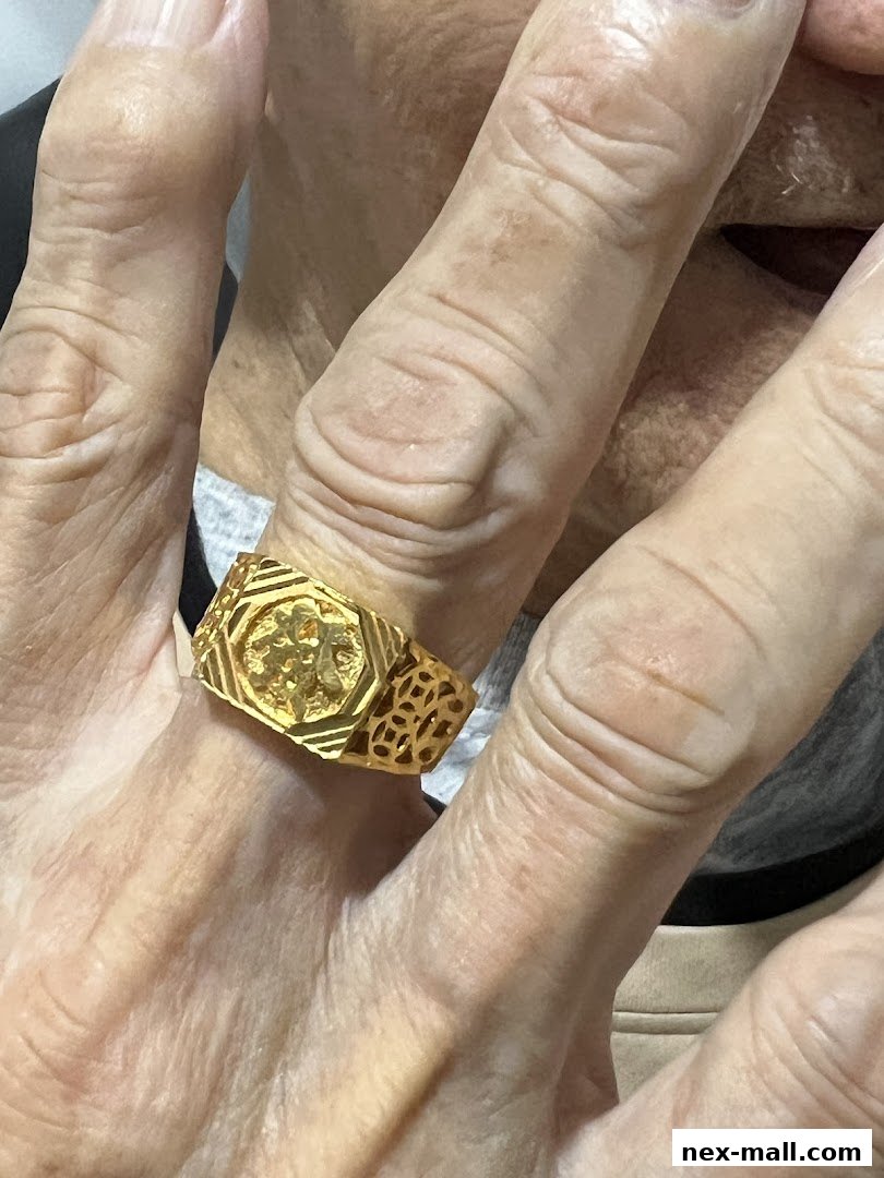 A close-up shot of a person's hand wearing a gold ring with intricate designs.