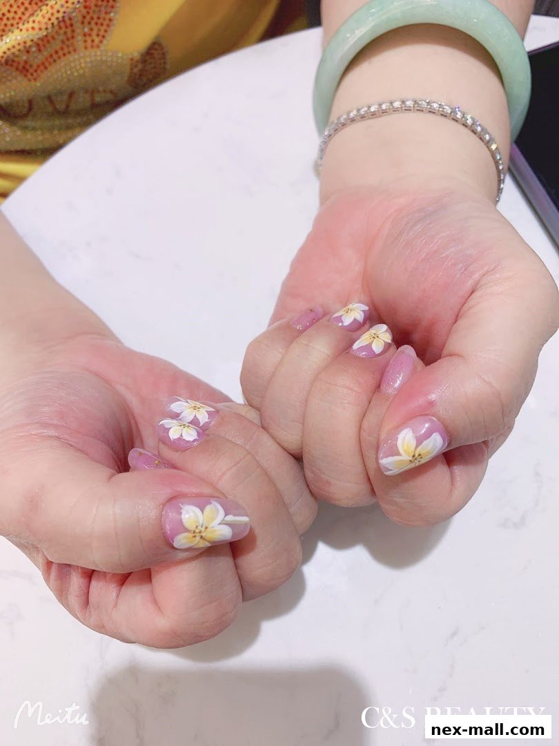 Close-up of hands with delicate floral nail art and jewelry.