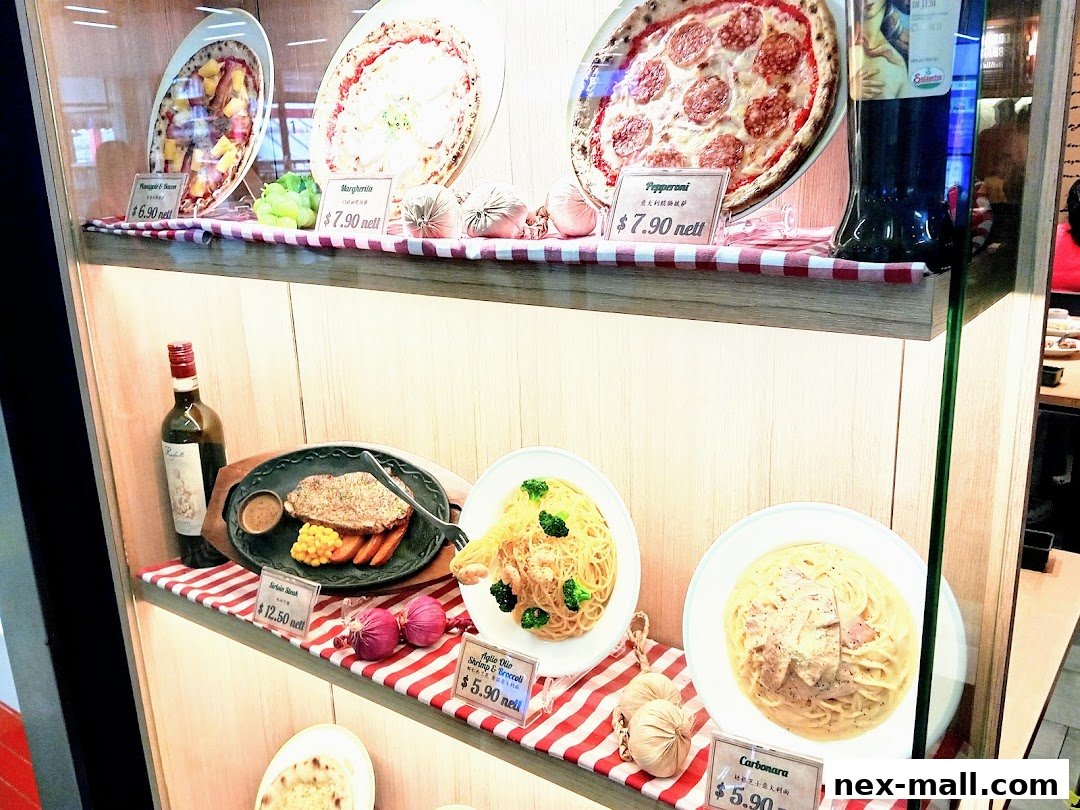A display case showcasing realistic food models of pizzas, steak, pasta, and a bottle of wine.
