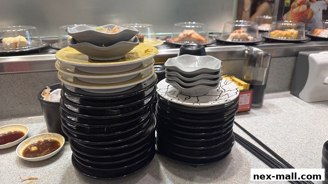 Stacks of used sushi plates and dipping sauce bowls on a conveyor belt sushi restaurant counter.