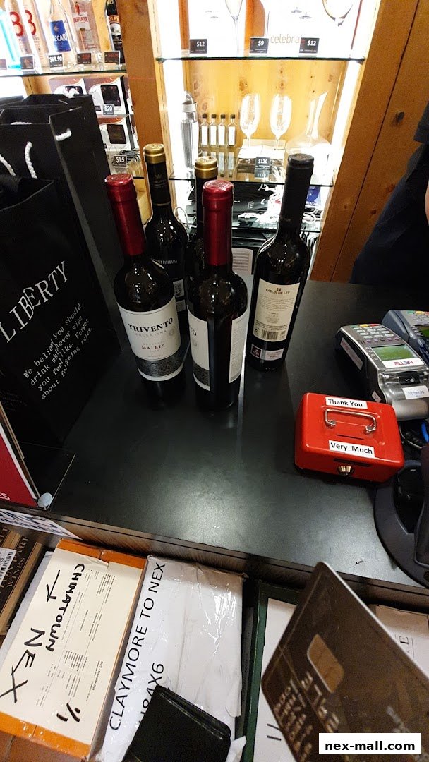 Bottles of wine and shopping bags are displayed on a counter with payment terminals.