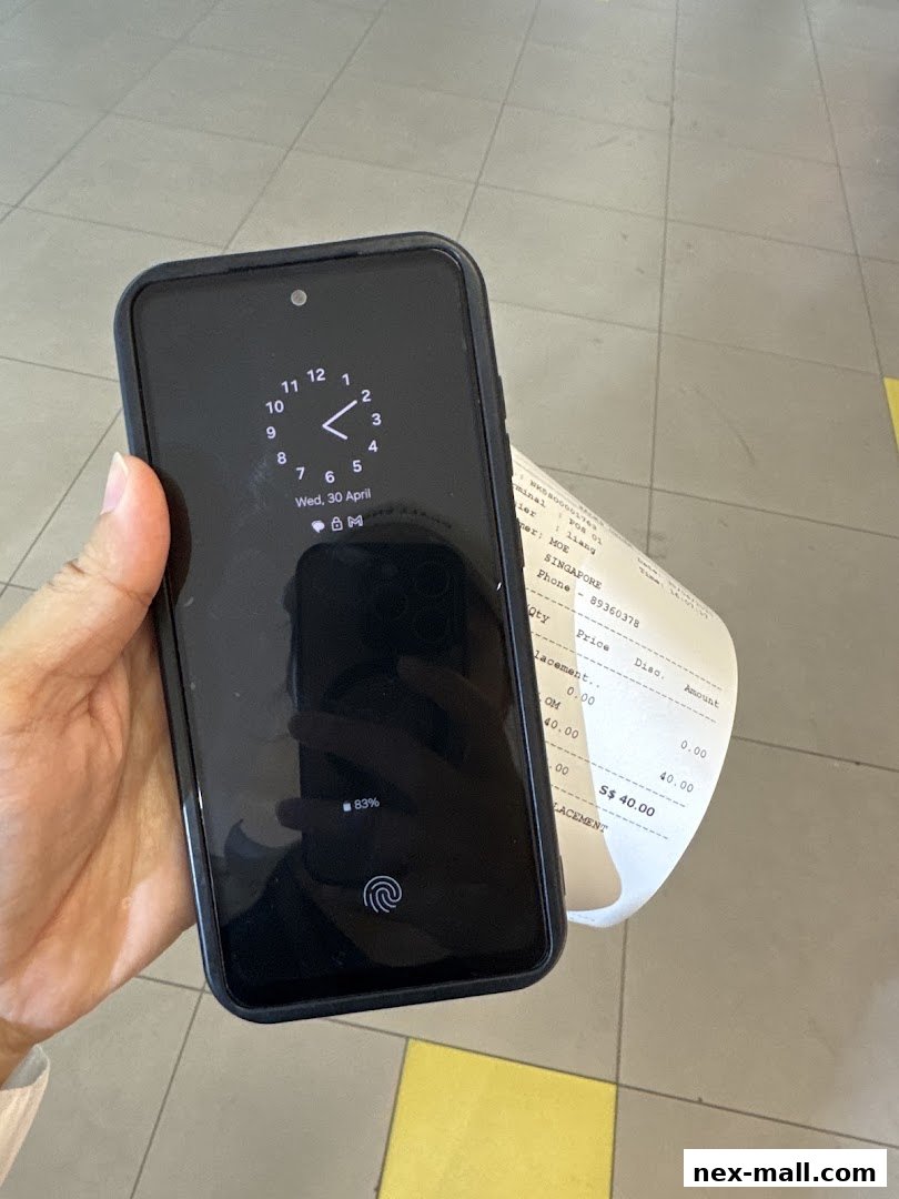 A hand holds a smartphone displaying a clock and battery percentage next to a receipt.