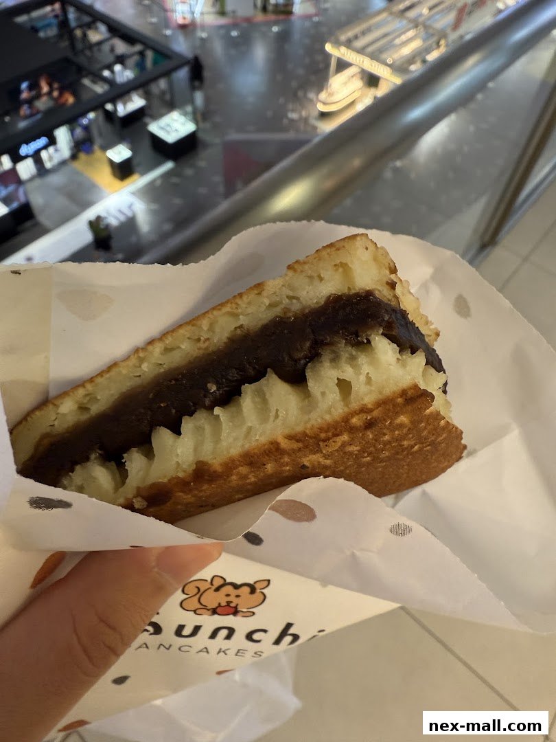 A hand holds a delicious red bean pancake from Munchi Pancakes.
