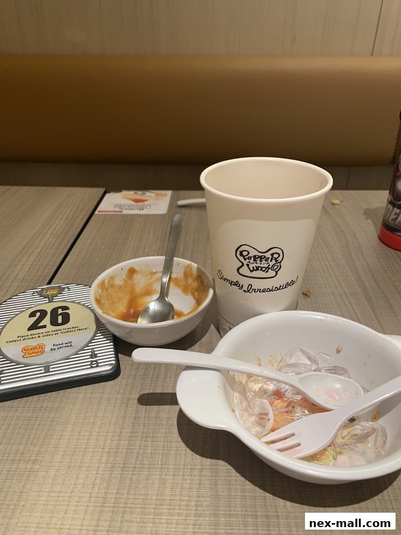 A table at Pepper Lunch with used dishes, a cup, and a table tracker.