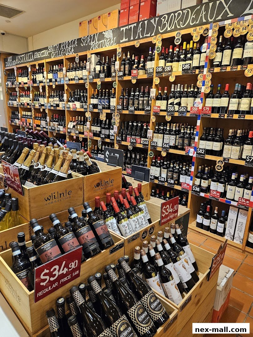 A wide selection of wine bottles displayed on shelves and in wooden crates, with price tags and origin labels.