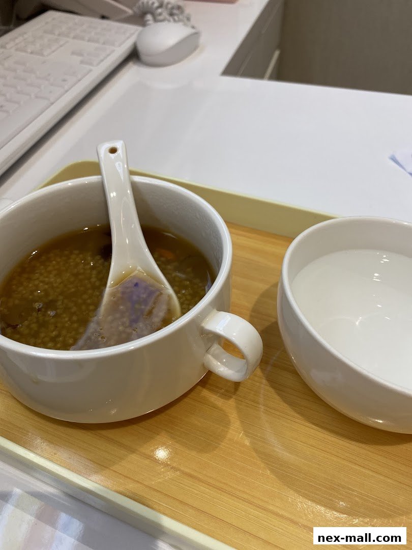 A bowl of porridge with a spoon and a cup of water on a tray.