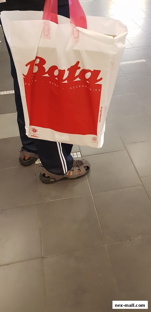 A person wearing sandals and holding a Bata shopping bag.