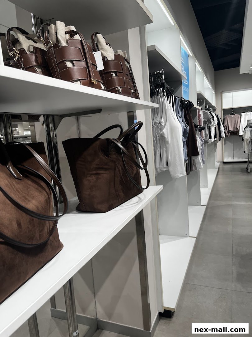 Stylish brown handbags and women's clothing displayed on shelves and racks inside a store.