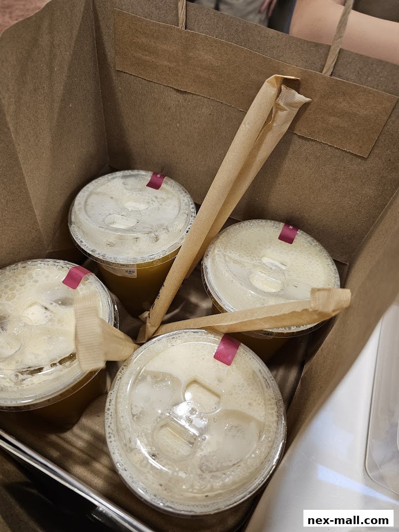 A brown paper bag filled with four takeaway drinks with straws.