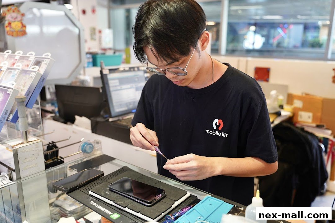 A technician works on repairing a smartphone at a counter with phone accessories displayed.