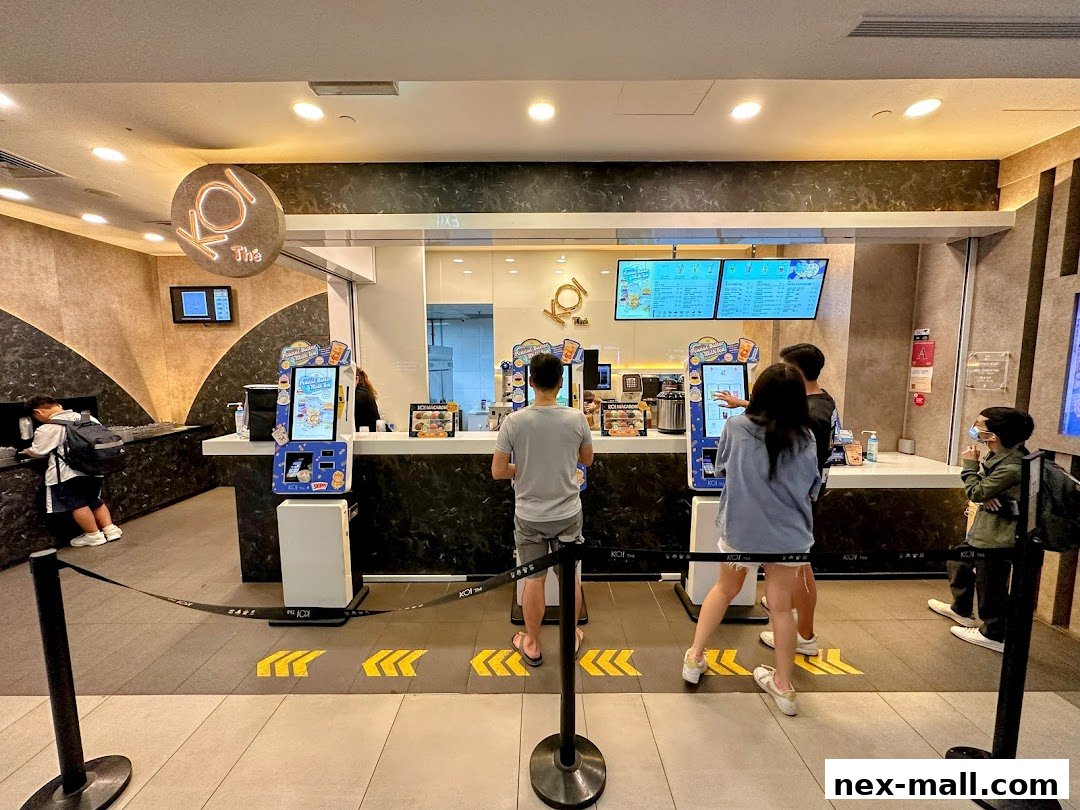 Customers queue at the KOI Thé counter with digital menus displayed above.