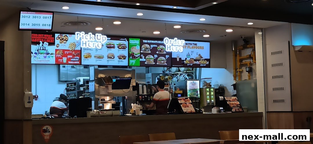 A MOS Burger counter with digital menus displaying burgers and a 'Pick Up Here' sign.