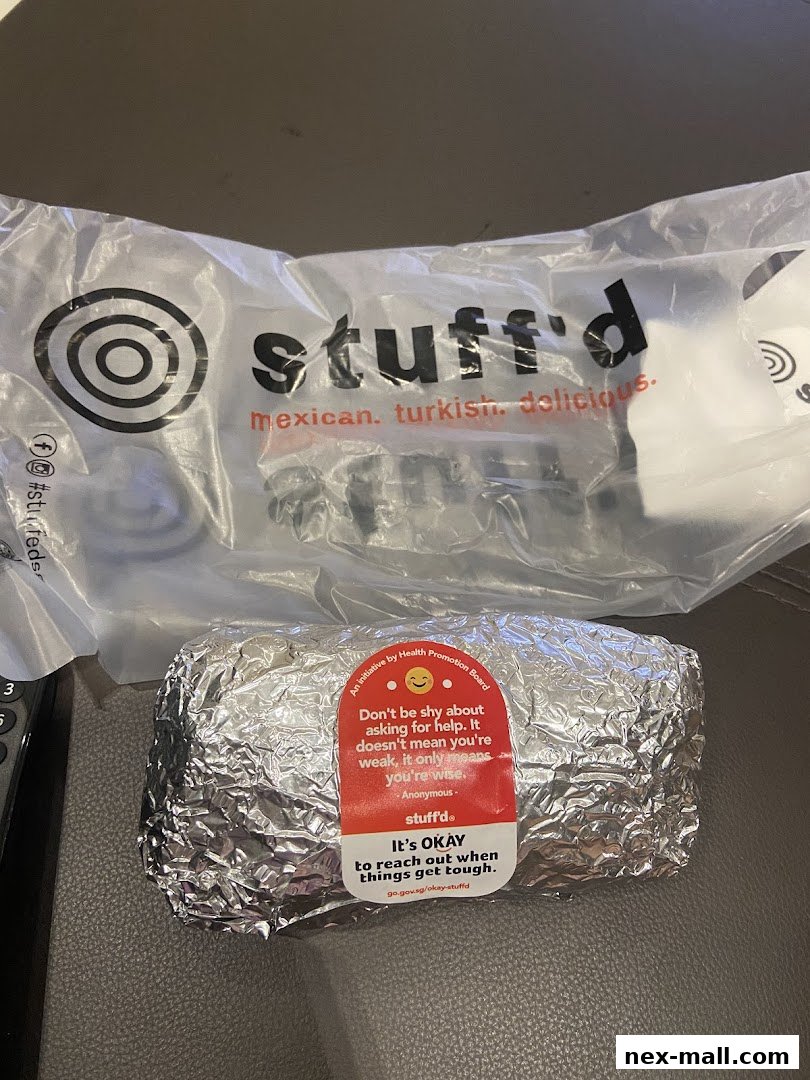 A foil-wrapped burrito from Stuff'd with a promotional sticker.