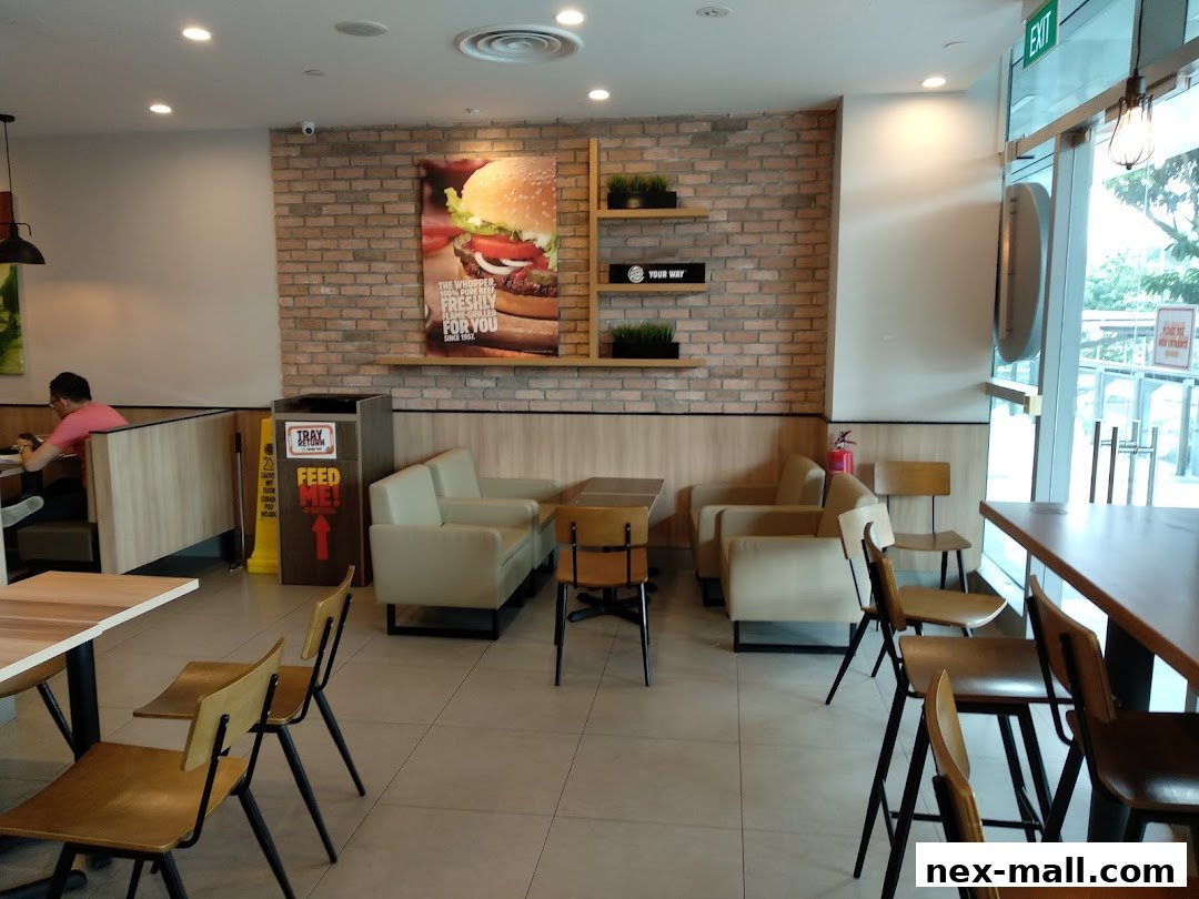 Interior of a Burger King restaurant with seating, a large Whopper advertisement, and a tray return station.