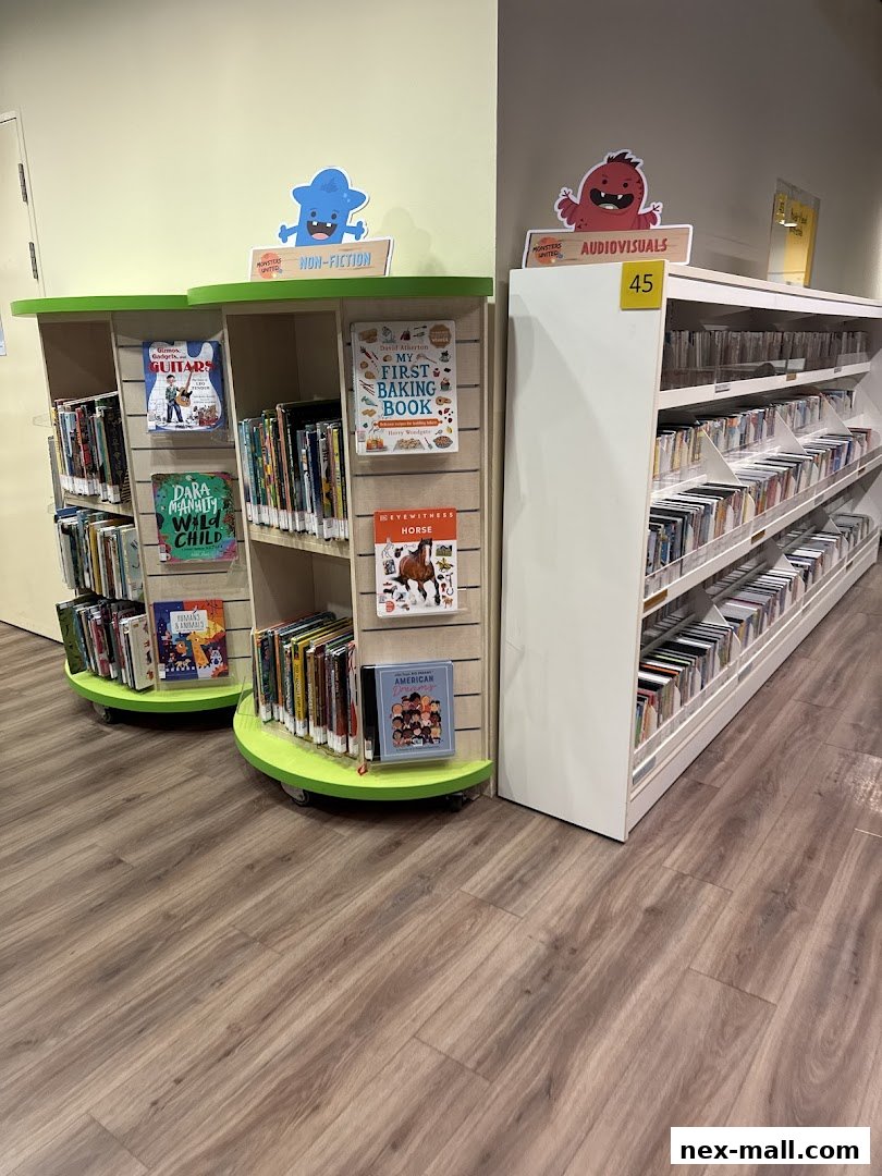Shelves of books and audiovisuals in a library, with colorful monster decorations.