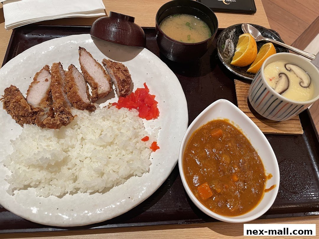 A delicious Japanese meal featuring crispy pork cutlet, rice, curry, miso soup, and chawanmushi.