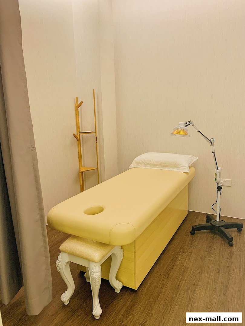 A treatment room with a massage bed, stool, and heat lamp.