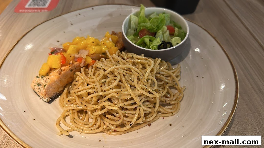 A plate of spaghetti with salmon, mango salsa, and a side salad.