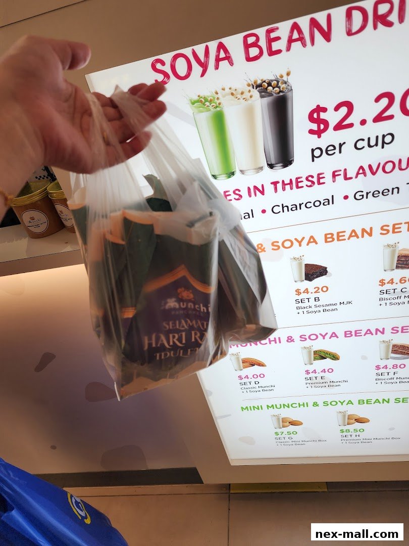 A hand holds a plastic bag filled with Munchi Pancakes items in front of a menu board.