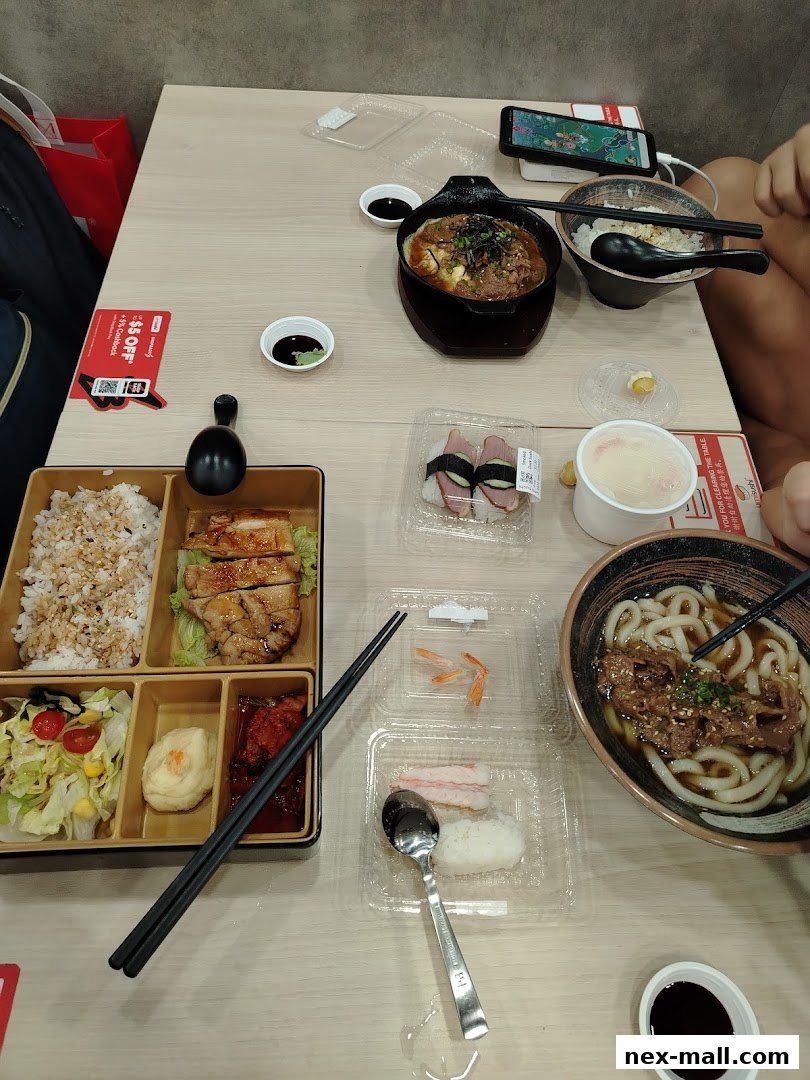 A table laden with various Japanese dishes including bento, sushi, and udon noodles.