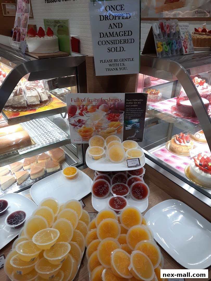 A display of various fruit jellies and cakes at Châteraisé, with a sign about dropped items.