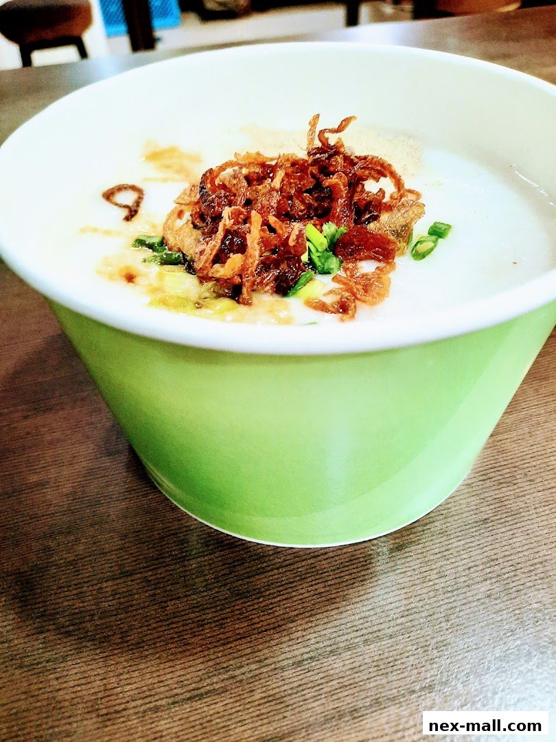 A close-up of a bowl of congee topped with crispy fried shallots and scallions.