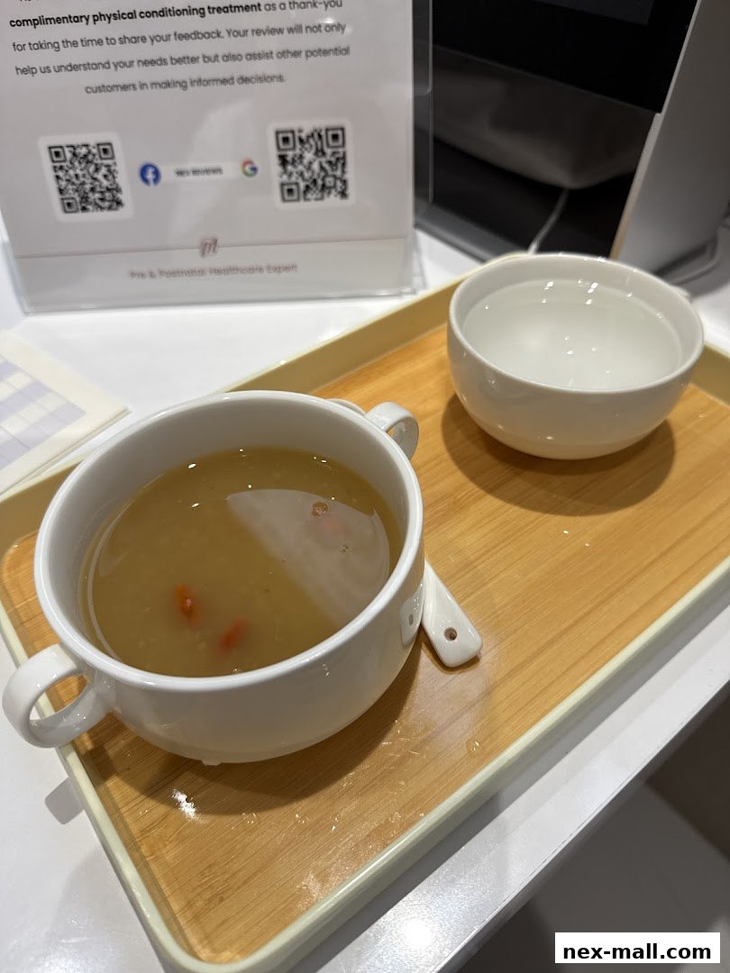 A bowl of soup and a glass of water served on a wooden tray.