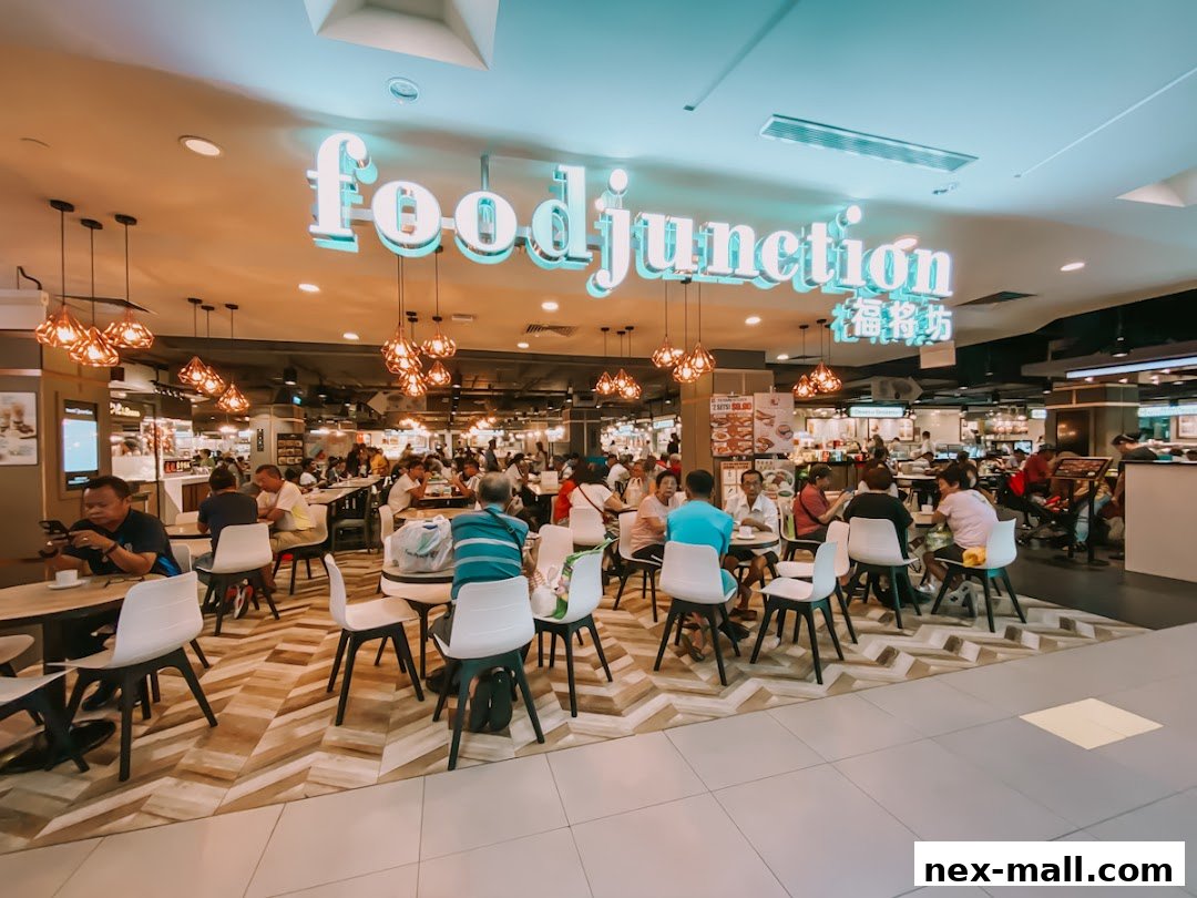 A bustling food court with many people dining at tables under decorative lighting.
