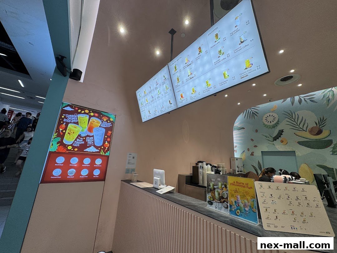 Interior view of a modern beverage shop with digital menus and a colorful wall mural.