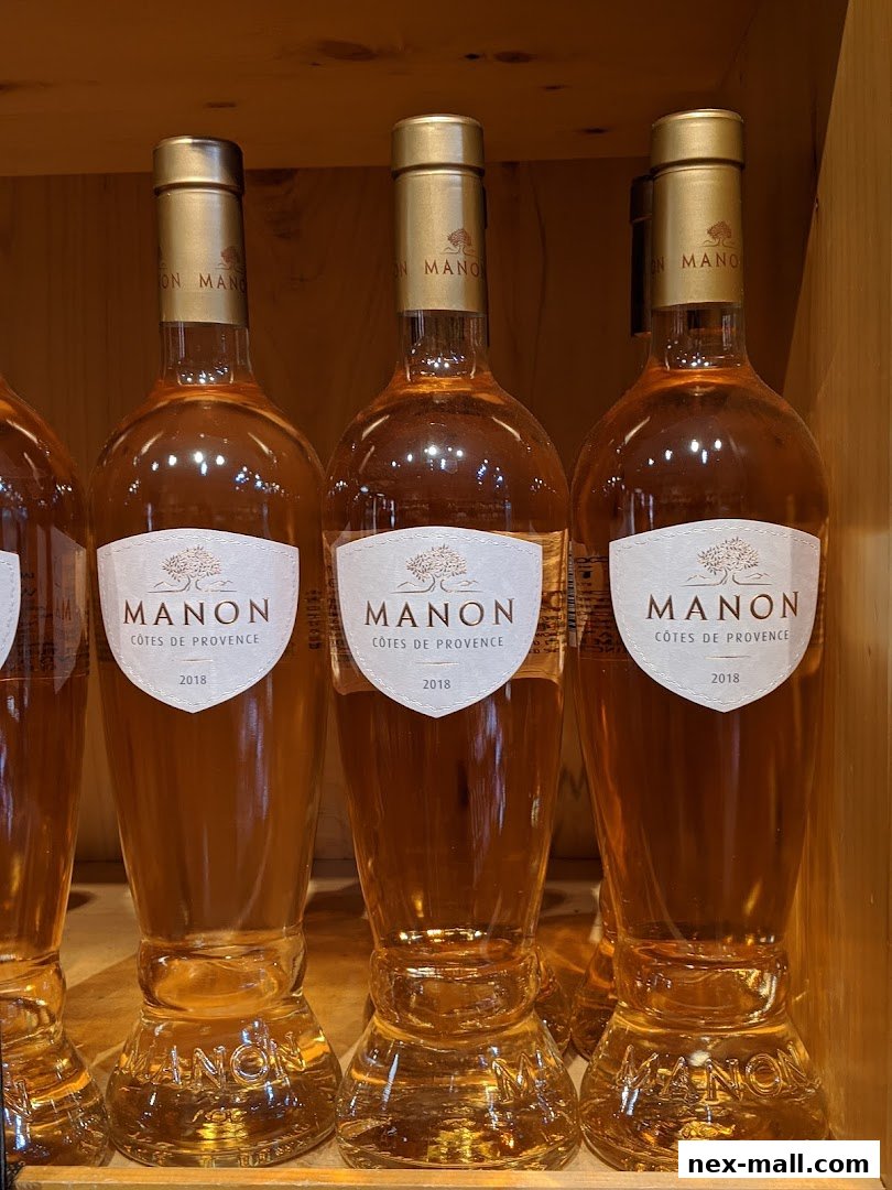 Three bottles of Manon Côtes de Provence rosé wine from 2018 displayed on a wooden shelf.