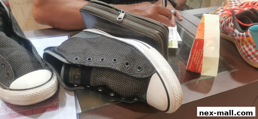 Close-up of Converse shoes and a wallet on a counter, with a price list visible.